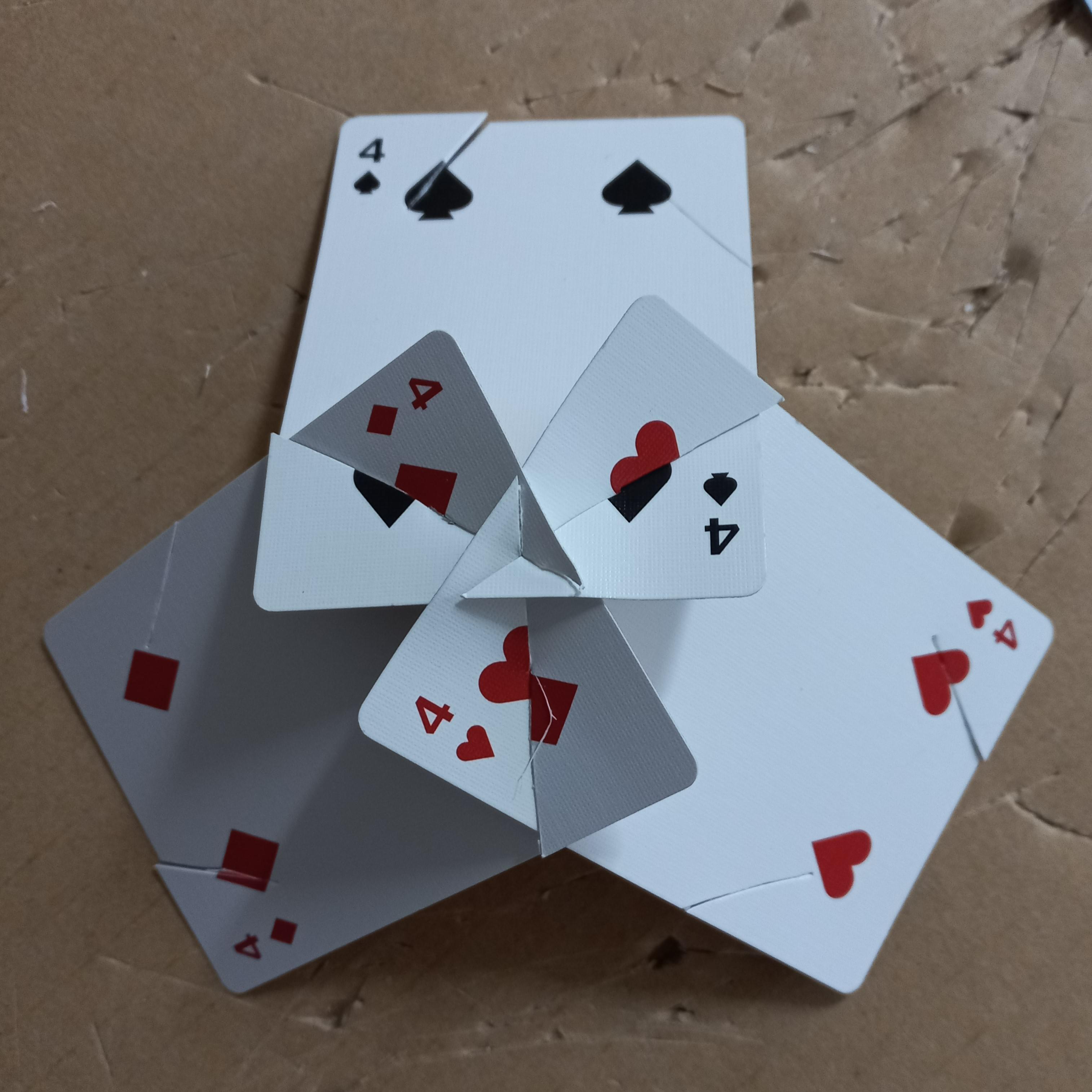 Three playing cards (4s of different suits) slotted together to form a single vertex. They are overlapped in a clockwise direction, with each card "cutting" through both of the other cards.